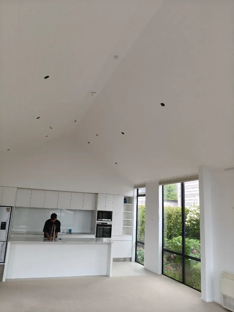 Painter working through a kitchen under a vaulted ceiling