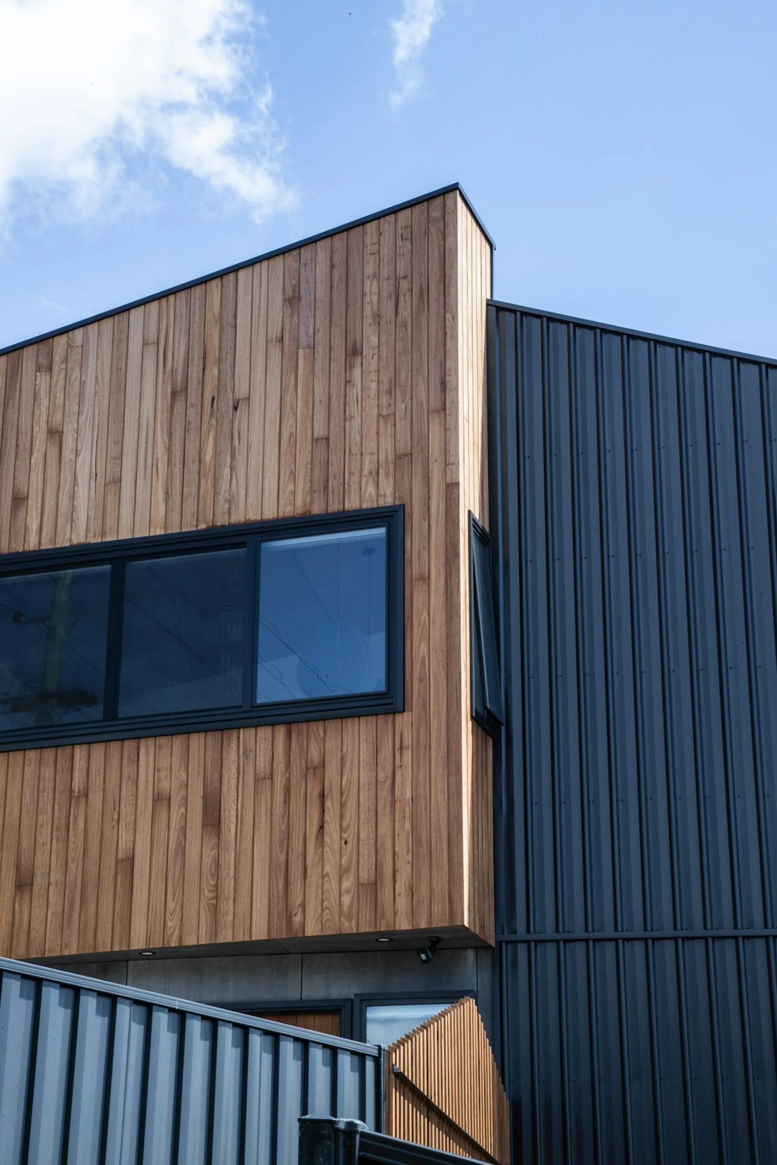 Exterior with painted dark cladding and stained cedar on the same house